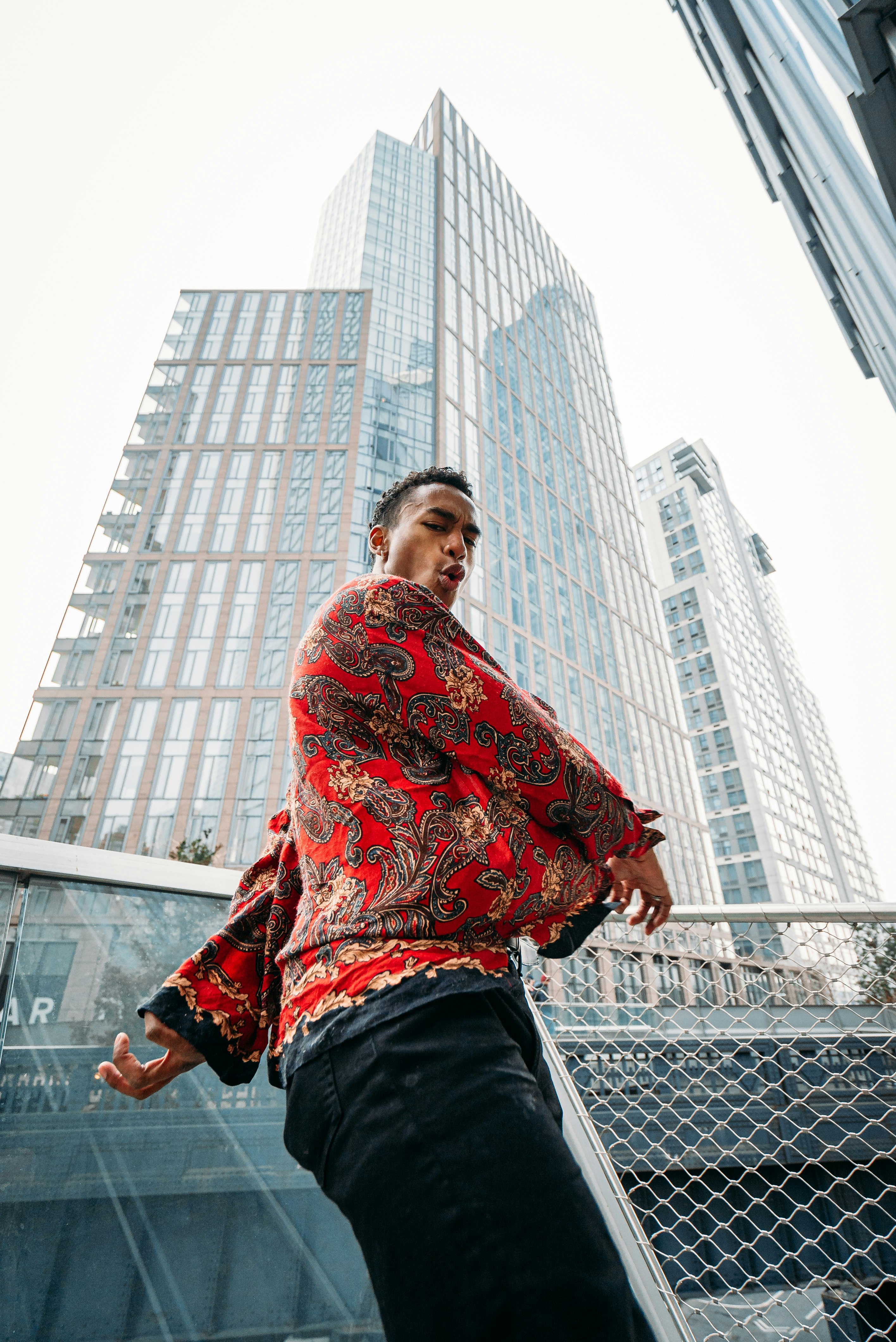 man in red and black floral sweater standing on top of building during daytime